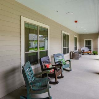 A shaded porch with several chairs arranged for relaxation.