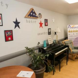 A cozy room with a piano, patriotic wall decorations, and comfortable seating.