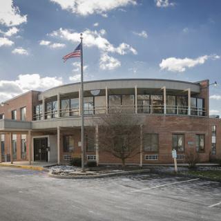 A modern brick building featuring a flagpole and surrounded by a clear sky.