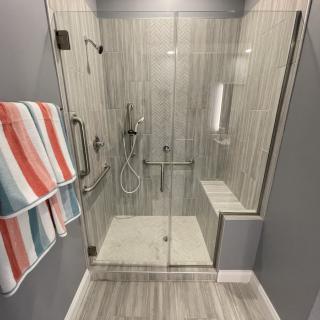 A modern bathroom shower with glass doors and striped towels.