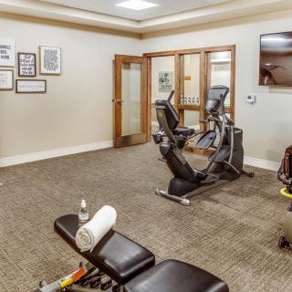 A small gym with a stationary bike, weights, and a workout bench.