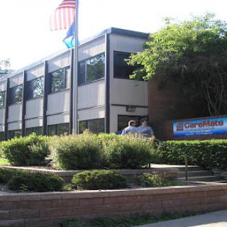 A view of a modern building with an American flag, surrounded by well-maintained landscaping.
