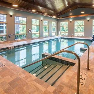 A modern indoor swimming pool with large windows and warm lighting.