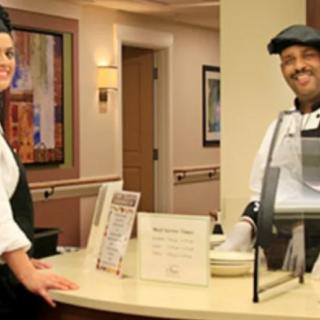 Two people in uniform smiling at a reception desk.