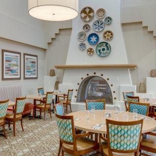 Cozy restaurant interior with decorative plates above the fireplace and arranged tables and chairs.