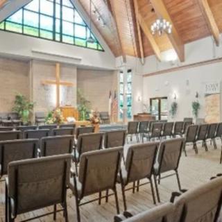 The interior of a church featuring rows of pews with a prominent cross at the front.