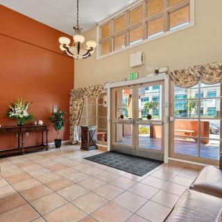 A spacious lobby with a chandelier, decorative plants, and large windows.