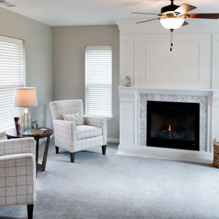 A cozy living room featuring a fireplace, two armchairs, and natural lighting.