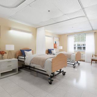 A well-lit hospital patient room featuring two adjustable beds and modern furnishings.