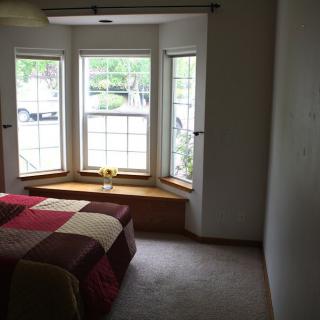 A cozy bedroom with a large window allowing natural light to fill the space.