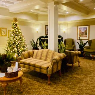 A cozy and inviting lobby decorated for the holiday season, featuring a Christmas tree and comfortable seating.