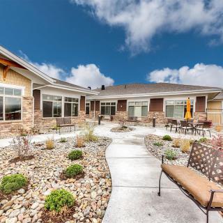 A modern house with a landscaped patio and outdoor seating under a cloudy sky.