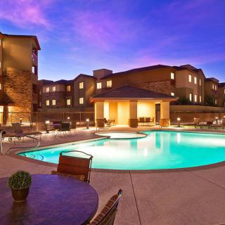 A well-lit swimming pool in a residential complex during twilight.