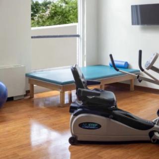 A compact home gym setup with a stationary bike, yoga mat, and exercise ball.