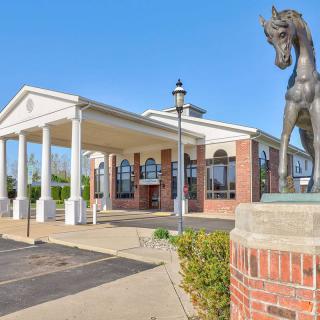 A building entrance featuring a horse statue and classical columns under a clear sky.