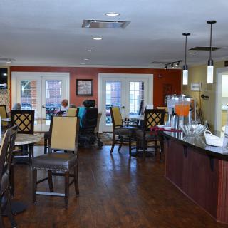 A modern dining area with tables, chairs, and a counter in a warm setting.
