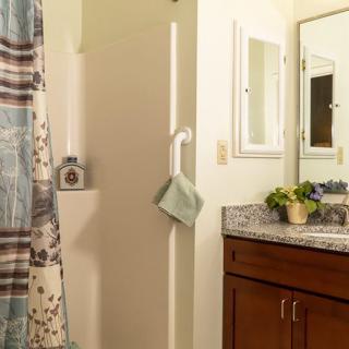 A cozy bathroom with a countertop, cabinet, and shower.