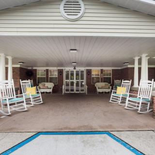 A covered porch with white rocking chairs and outdoor seating.