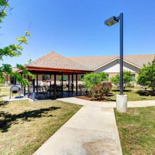 A scenic outdoor area featuring a covered pavilion, surrounded by pathways and landscaping.