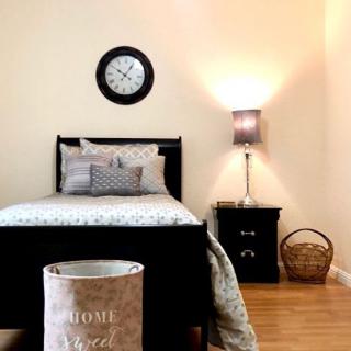 A cozy bedroom with a single bed, nightstand, and wall clock.