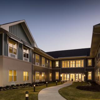 A well-lit residential building with a pathway at dusk.