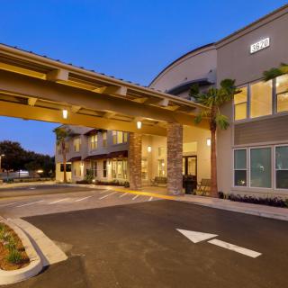 Exterior view of a hotel entrance illuminated during the evening.
