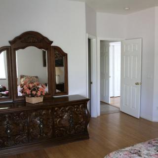 A cozy bedroom featuring a wooden dresser with an ornate mirror and a floral arrangement on top.