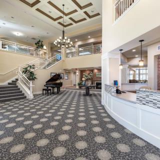 A spacious hotel lobby with a grand staircase, piano, and chandelier.