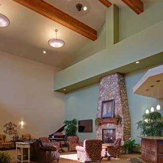 A spacious living room with high ceilings, featuring a stone fireplace, wooden beams, and comfortable seating.