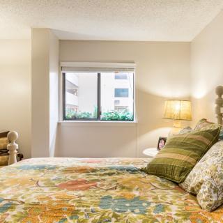 A cozy bedroom with a colorful bedspread and soft lighting.