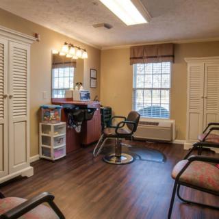A well-lit salon interior with chairs and a mirror station.