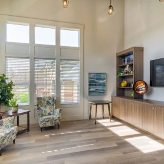 A spacious and modern living room featuring armchairs, a television, and large windows allowing for ample natural light.