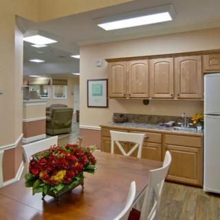 A cozy kitchen and dining area featuring wooden cabinets, a refrigerator, and a dining table adorned with flowers.