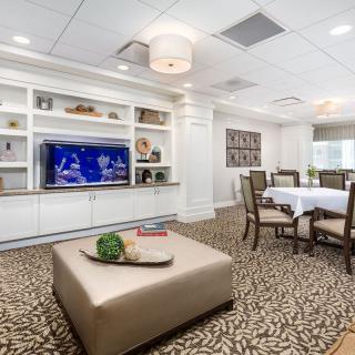 A modern living and dining area featuring a television, bookshelves, and elegant decor.