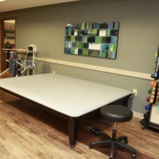 A physical therapy room featuring a large treatment table and exercise equipment.