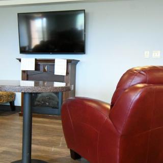 A modern living room with a wall-mounted television and a comfortable red chair.