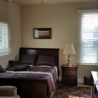 A cozy bedroom with a bed, nightstand, lamp, and window.