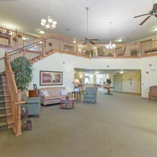 A spacious lobby area featuring comfortable seating, a staircase, and elegant chandeliers.
