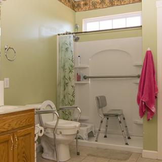 A bathroom with accessibility features, including a shower chair and safety bars.