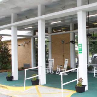 Covered porch entrance with rocking chairs and white columns.