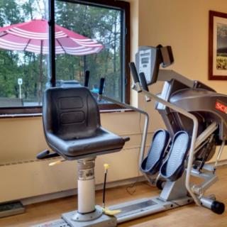 A gym interior with a reclined exercise bike positioned near a window.
