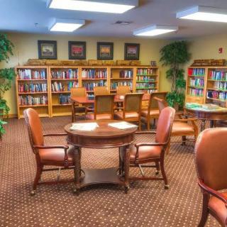 Cozy library reading room with bookshelves, tables, and chairs.