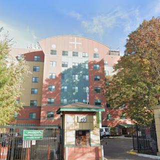 A multi-story apartment building with a modern architectural design, surrounded by trees.