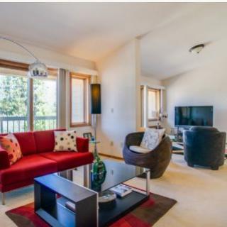 A modern living room with a red sofa, glass coffee table, and large windows.