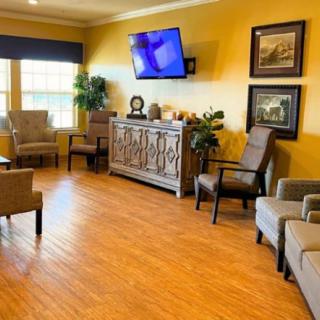 A cozy waiting room with comfortable chairs, a television, and decorative art on the walls.