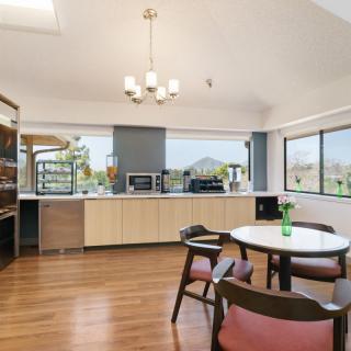 A modern kitchen and dining area with wooden flooring, large windows, and minimalist design.