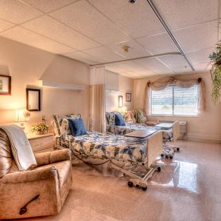 A well-lit hospital room featuring two beds and comfortable chairs, designed for patient care.