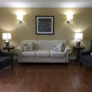 A cozy living room with a white sofa, flanked by two armchairs and lit by lamps on either side.