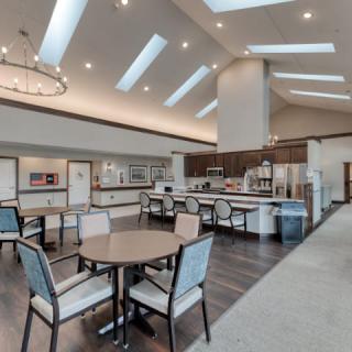A modern dining area with skylights and a chandelier, featuring tables and chairs arranged in a spacious layout.