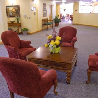 A cozy seating area in a lobby with red chairs and a wooden table decorated with flowers.
